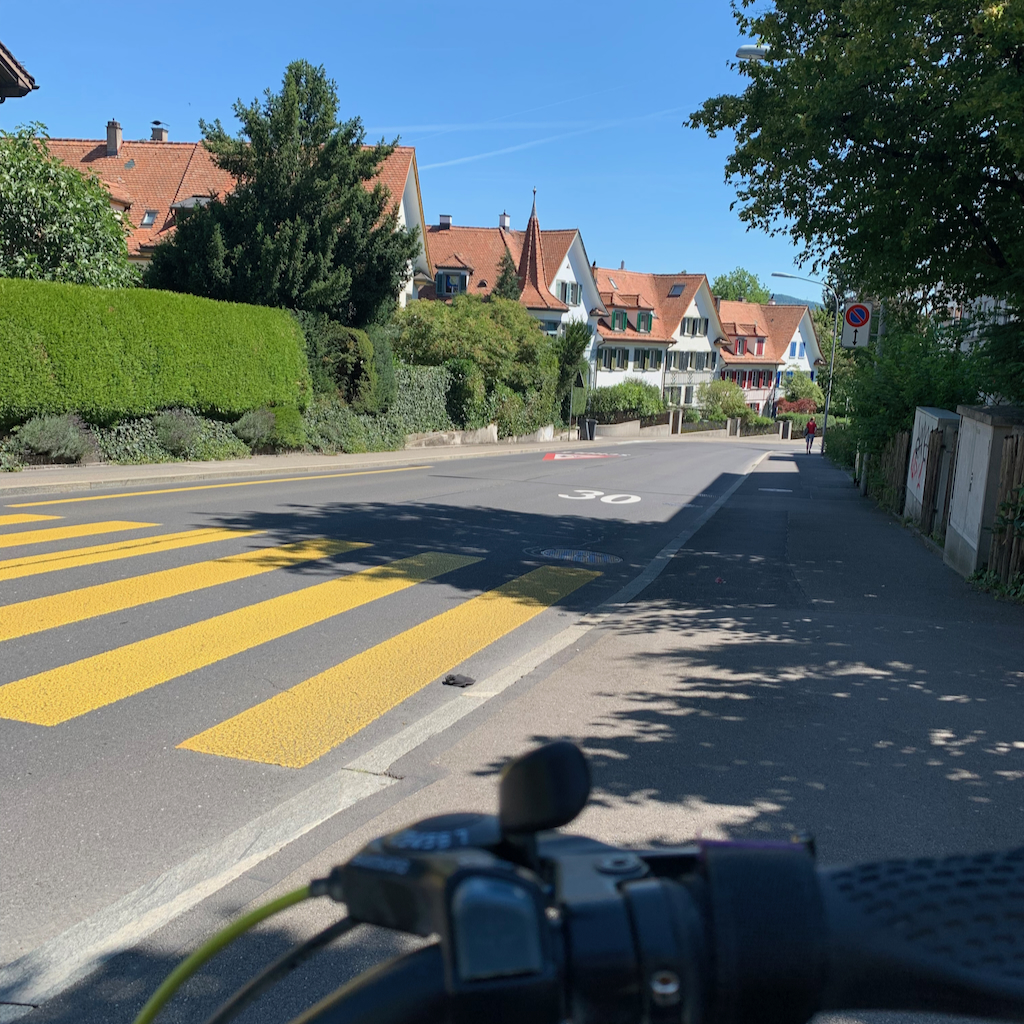 En väg med ett gult övergångsställe, genom ett prydligt villaområde i utkanten av Zürich i Schweiz