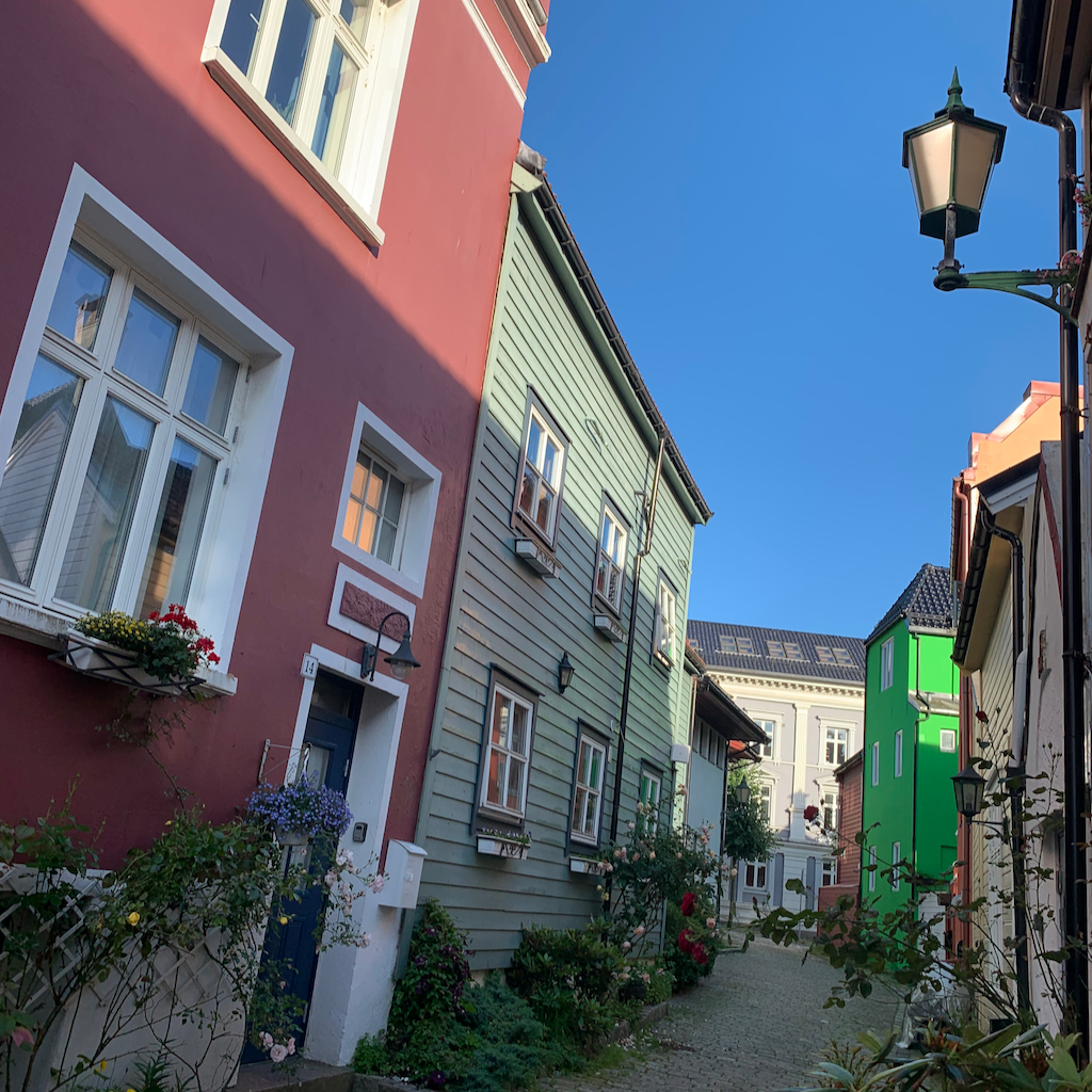 Illgrönt hus bland andra hus i Bergen