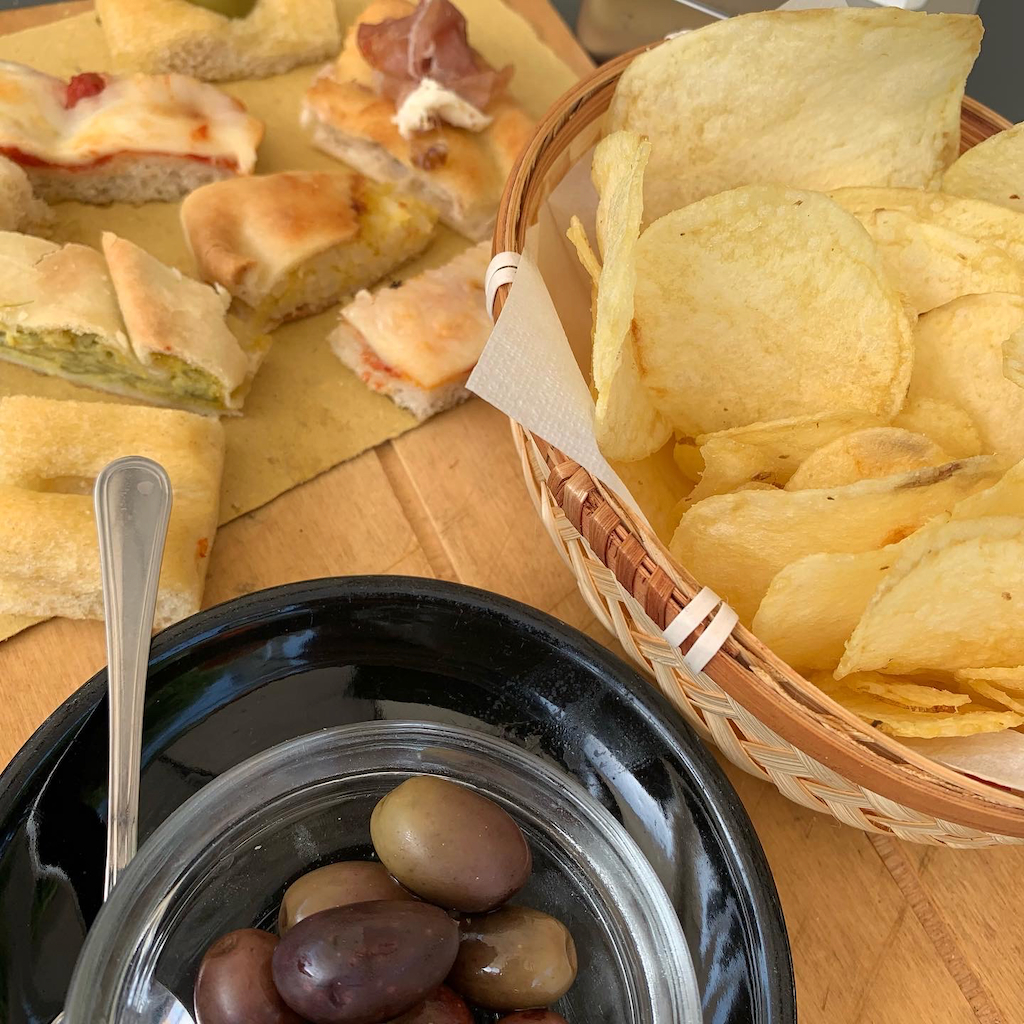 Aperitivo bestående av chips, oliver och små focacciasnittar