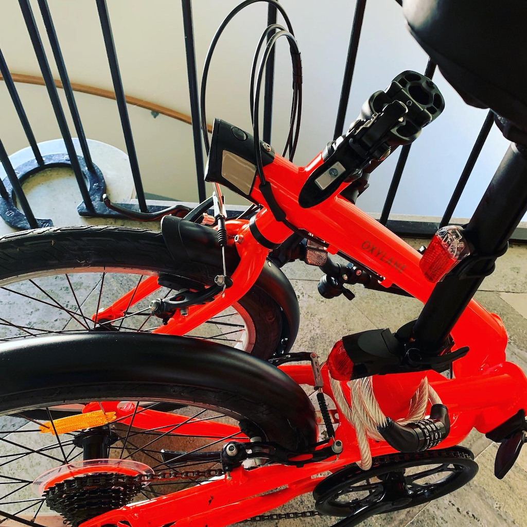 En ihopfälld röd eller orange cykel från Decathlon.