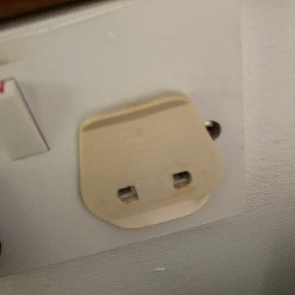 En plastbricka som fungerar som adapter för svenska stickproppar på Seychellerna