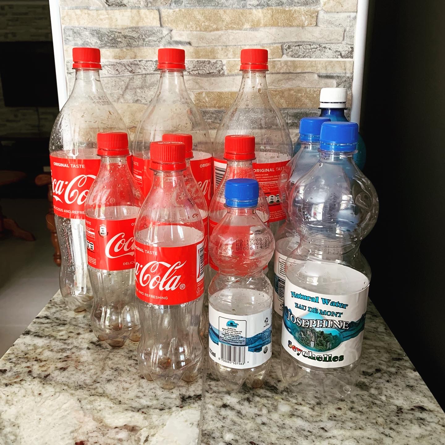 En samling tomma vatten- och colaflaskor som står på en köksbänk i ett guest house på Seychellerna