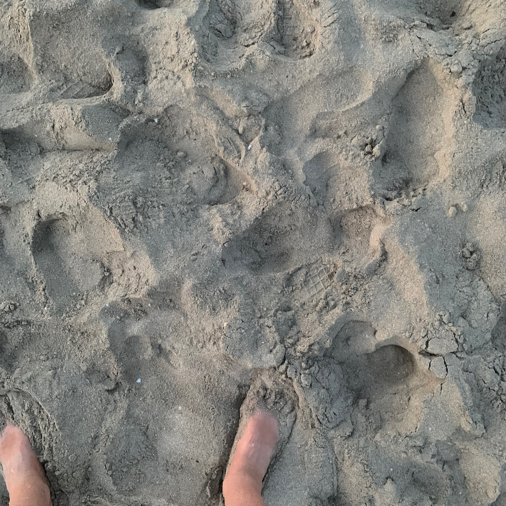 Mina fötter i sanden på Mondello beach på Sicilien i Italien