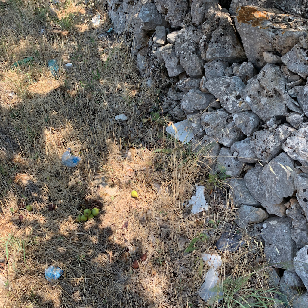 En vackert staplad stenmur i en i övrigt väldigt nedskräpad vägren utmed vägen från Carvignio och Ostuni i Apulien Italien