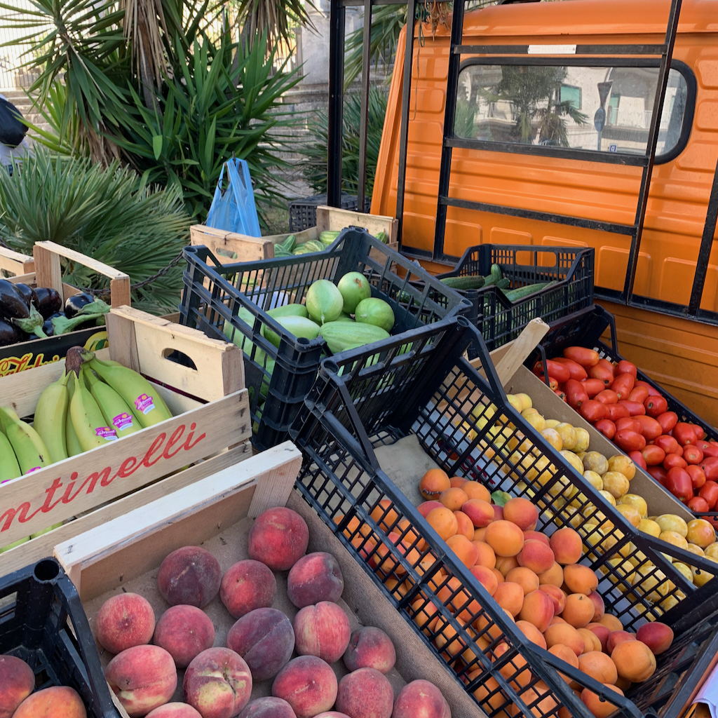 En liten orange lastbil med lokalt odlande frukter och grönsaker i Ostuni i Apulien Italien