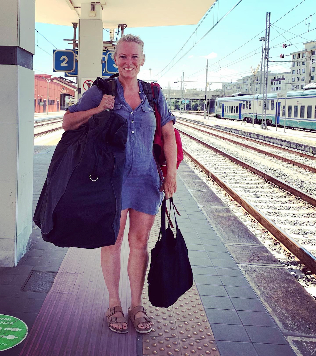 Jag med min cykel i en väska över axeln på en tågperrong i Italien