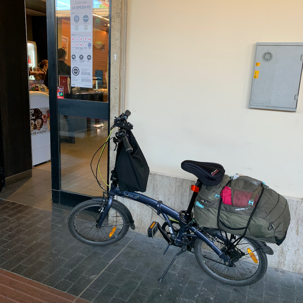 En fällbar cykel med packning på pakethållaren vid en tågstation i Italien