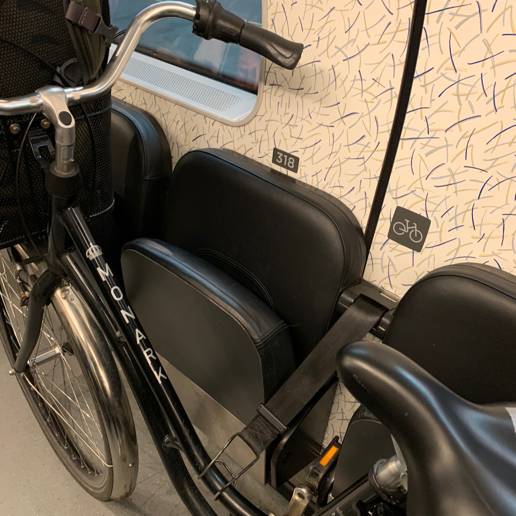 En fastspänd cykel med en ryggsäck i cykelkorgen på Öresundståget på väg till Danmark.
