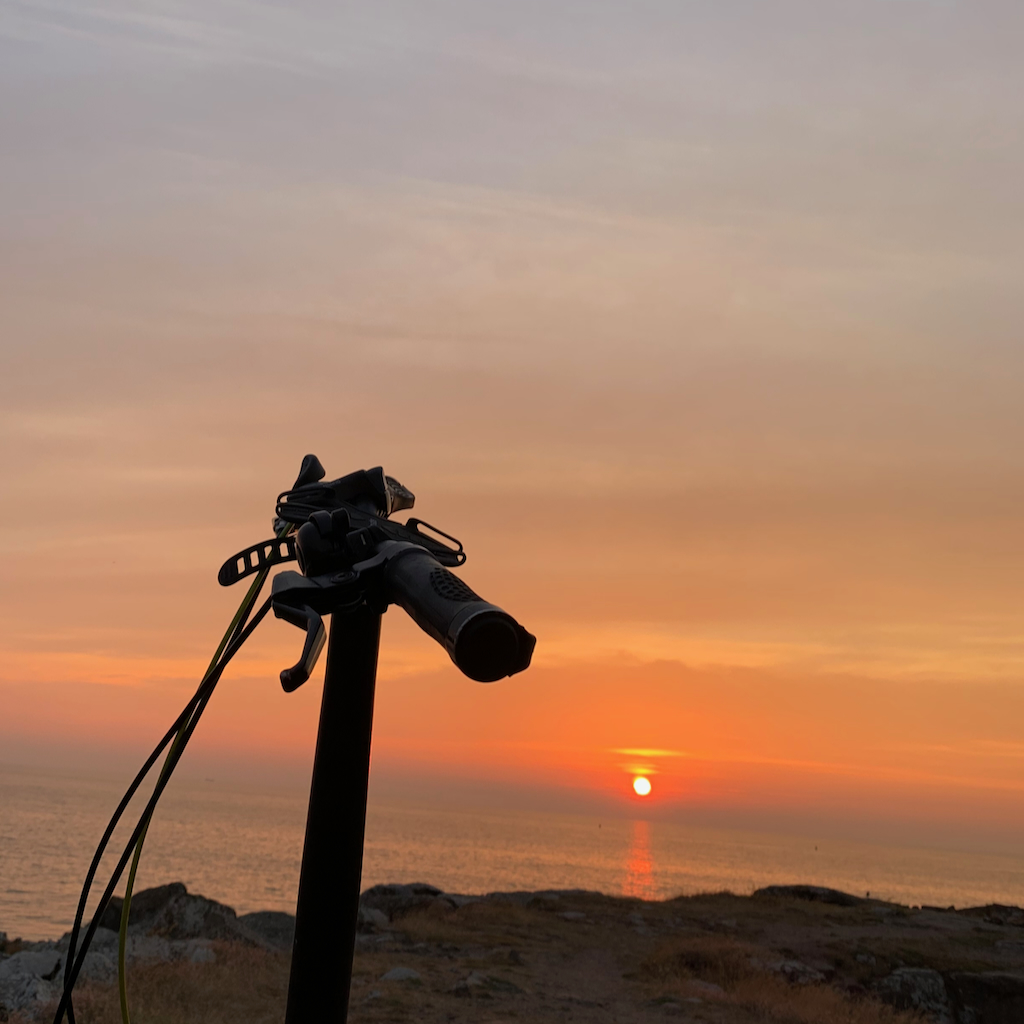 Ett cykelstyre med en korallröd solnedgång i Varberg