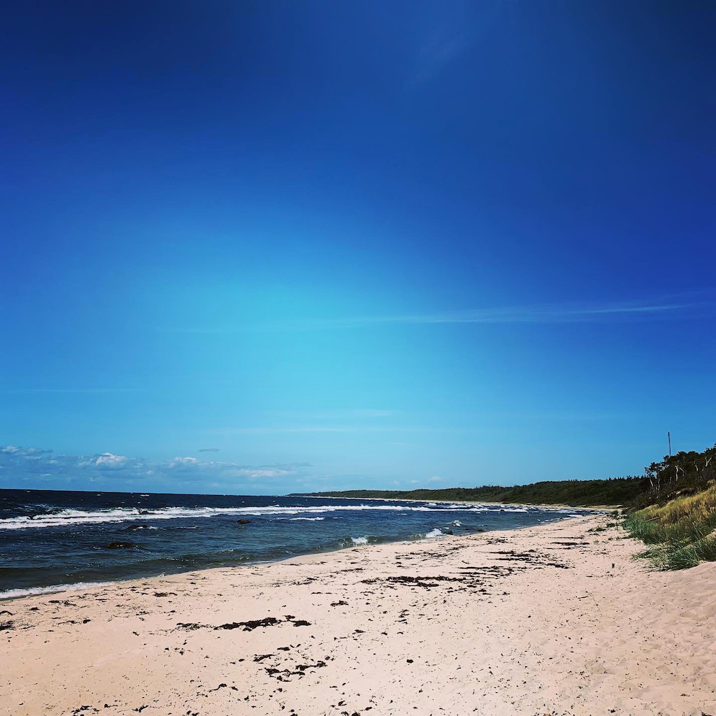 En finkornig sandstrand och klarblå himmel på Bornholm i Danmark