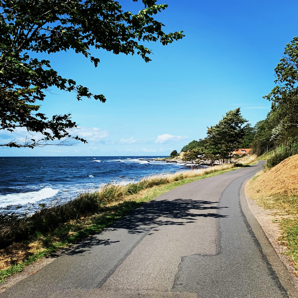 En smal asfalterad väg utmed ett blått hav på Bornholm i Danmark