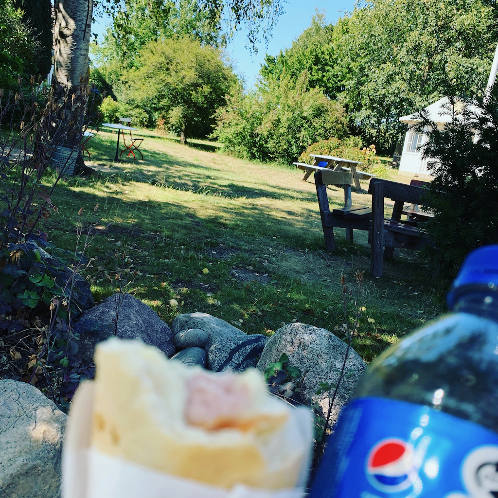 En french hotdog och pepsi i petflaska i en trädgårdscafemiljö på Bornholm i Danmark