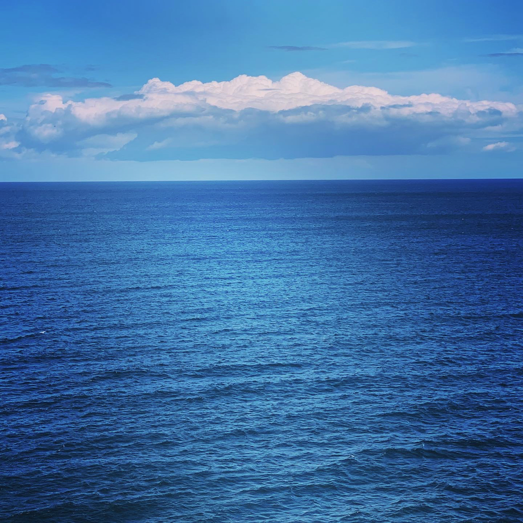 En utsikt över ett blått hav, en blå himmel och en hatt av moln från Bornholm i Danmark