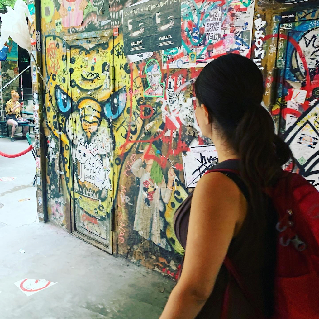 En kvinna med ryggsäck står och tittar på väggkonst på Haus Schwarzenberg i Berlin Tyskland