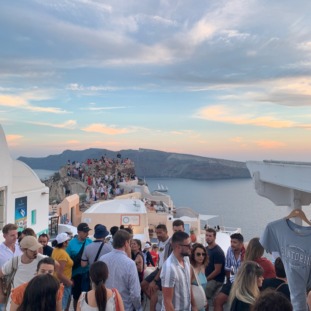 Hundratals turister som trängs i solnedgången i Oia på Santorini i Grekland