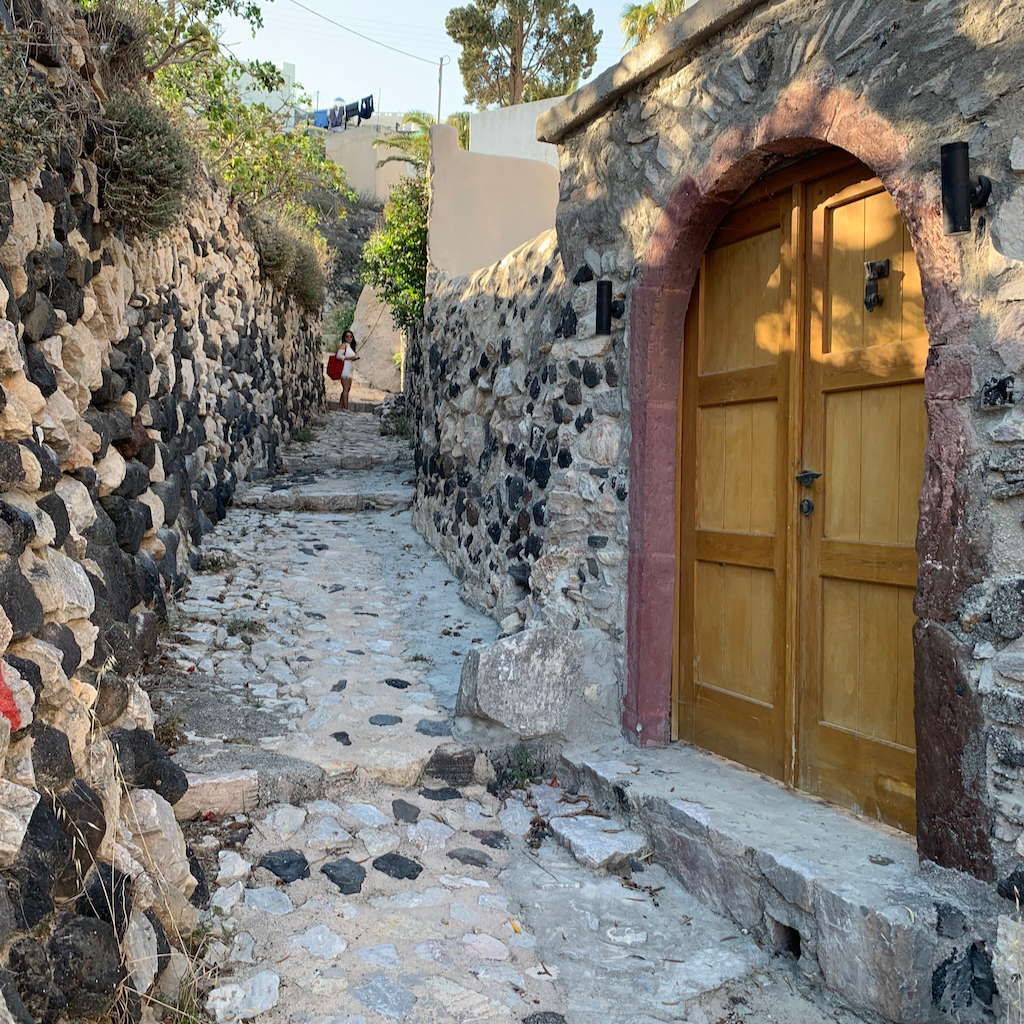 En träport vid en stenig gränd på väg till restaurangen Metaxi Mas i Exo Gonia på Santorini i Grekland
