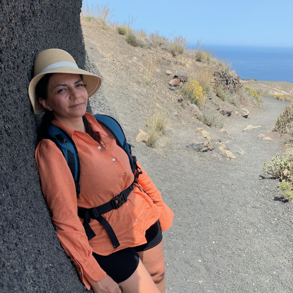 En kvinna som står och pustar ut i skuggan utmed vandringsleden mellan Fira och Oia på Santorini i Grekland