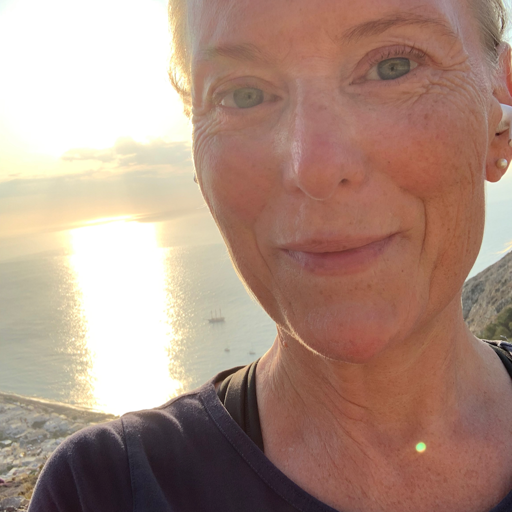 Ett svettigt självporträtt med havet i bakgrunden från en morgonpromenad uppför berget Mesa Vouno vid Kamari Beach på Santorini i Grekland