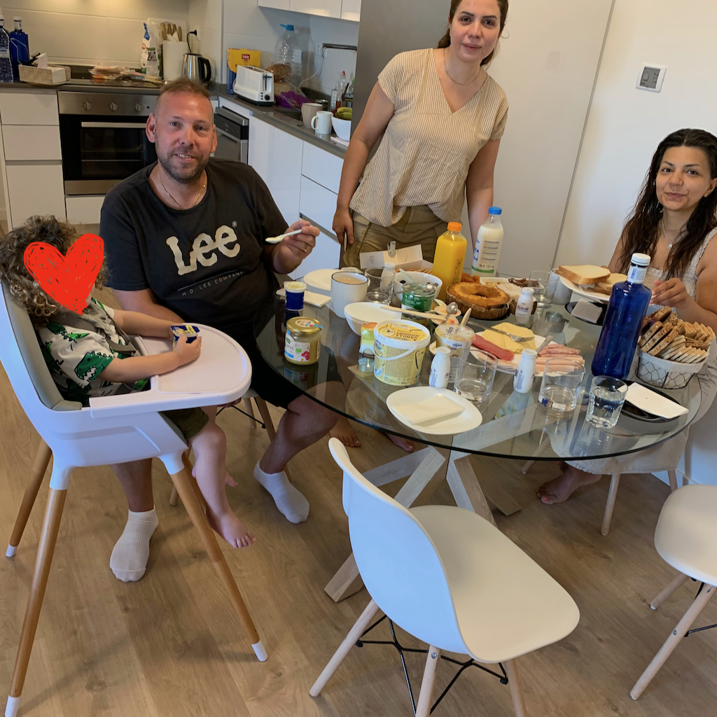 En barnfamilj med gäster vid ett dukat frukostbord i Spanien