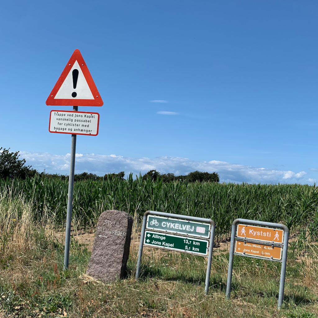 Tre skyltar som anger cykelväg, vandringsled och att man skall se upp för korsande cyklar på Bornholm i Danmark