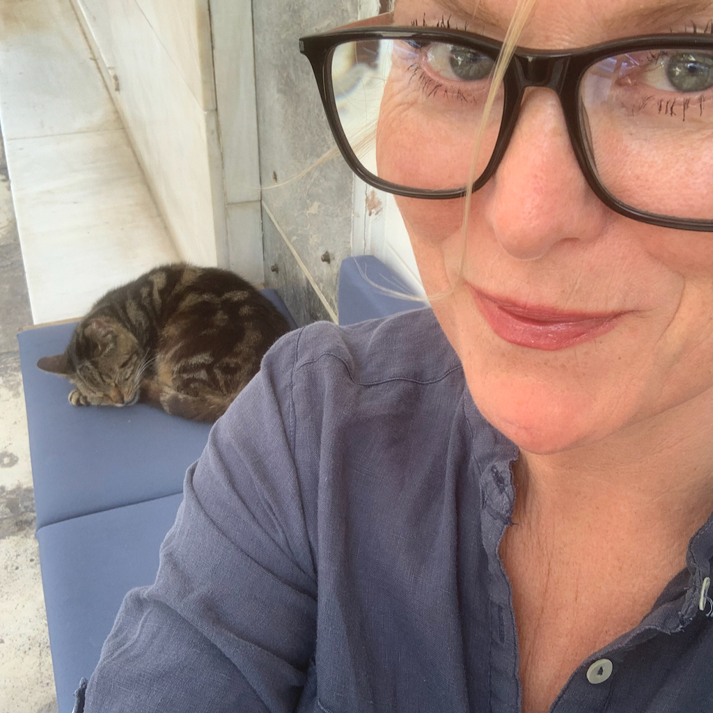 En kvinna och en sovande katt på ett café i Aten.