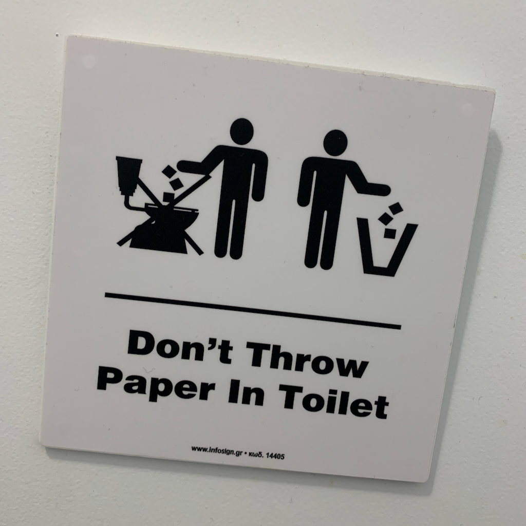 En skylt som talar om att man inte kan slänga toalettpapper i toaletten i Aten.