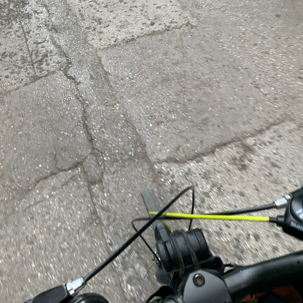 En cykel på en lappad och lagad väg av asfalt i Aten.