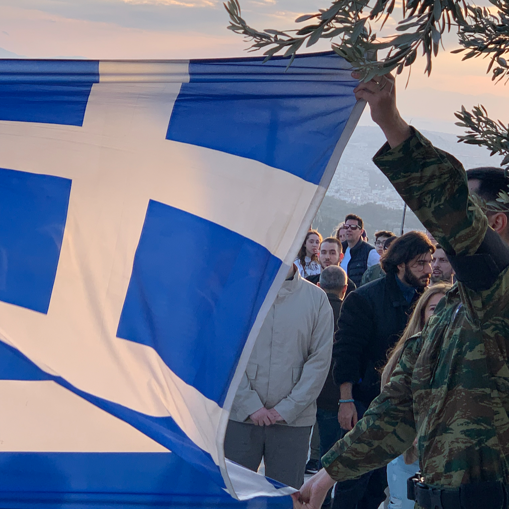 En grekisk flaggnedtagningscermoni vid solnergången på Mount Lycabettus i Aten.